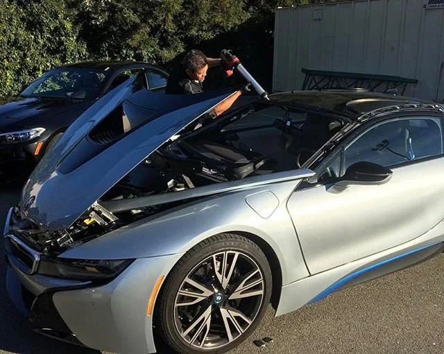 Auto Glass In Motion technician replacing a windshield and working on a BMW i8 vehicle